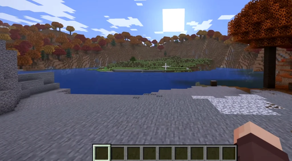 Looking across the calm crater lake toward the circular central island framed by autumn hills in Minecraft 26.3
