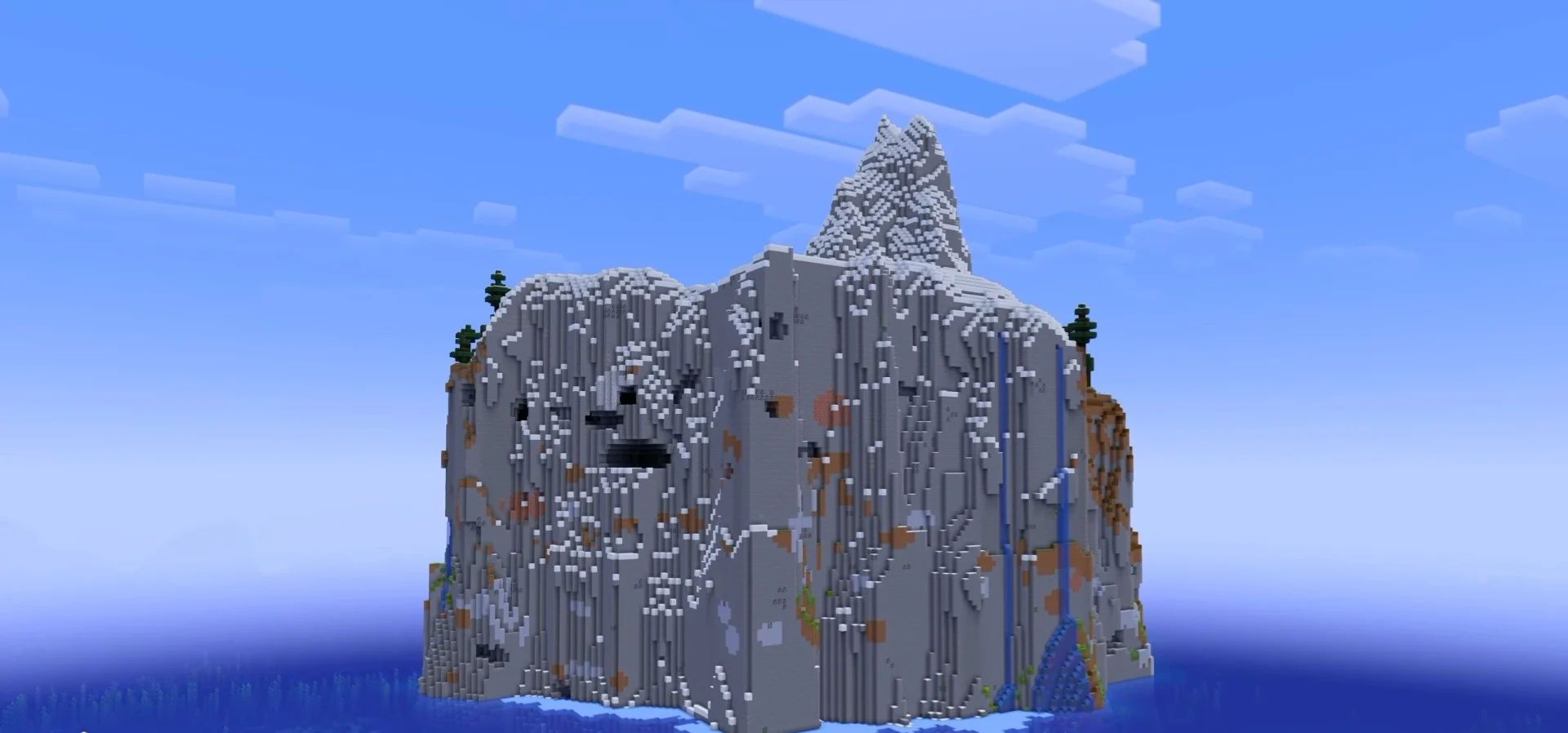 A sheer stone mountain cliff island with a snowy peak rising from the ocean